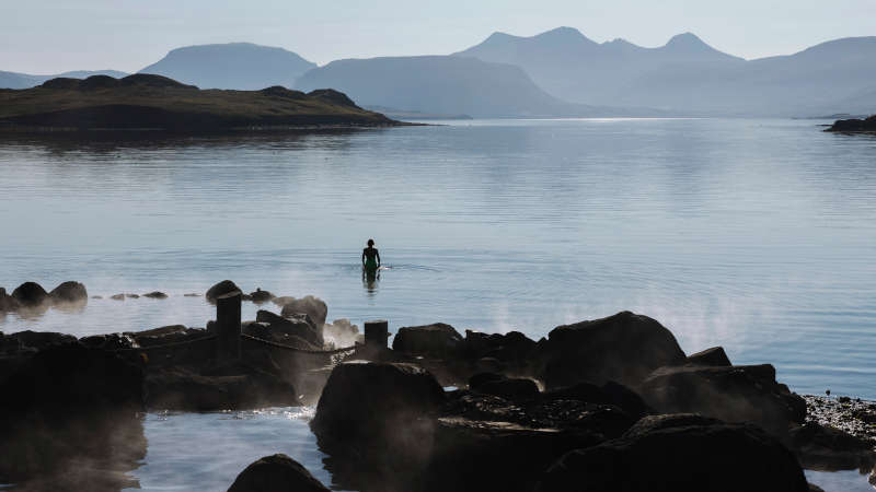 Hvammsvik spa in Iceland with woman swimming in the ocean