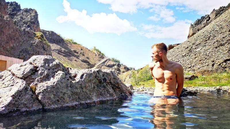 Canyon Baths in Husafell, young guy chilling in geothermal pool in the sun