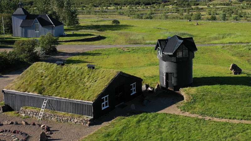 Husafell black timber building with a grass rooftop in the grass fields on a heritage site