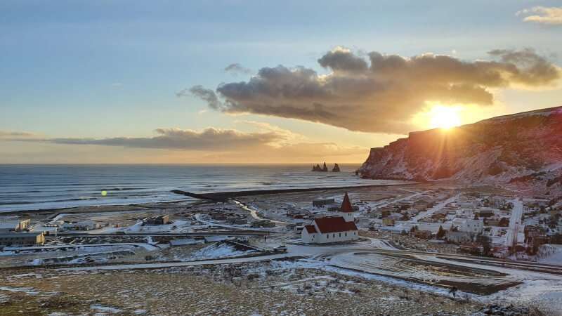 Vik Village, church on the hill and black beach seen on the sunset time