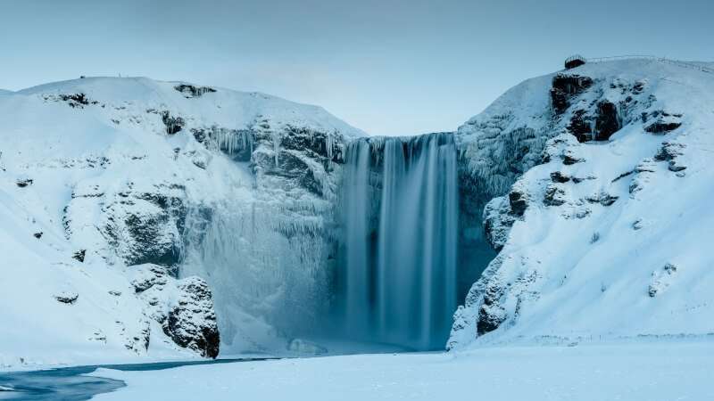 Skógafoss Winter waterfall with snowy hills around