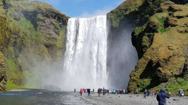 Skógafoss waterfall in Iceland on a sunny day with plenty of people