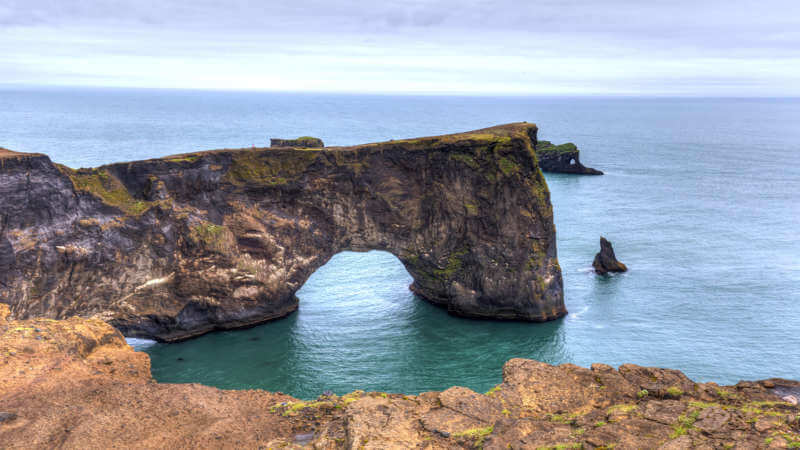 Dyrhólaey sea arch in Iceland on a calm cloudy day