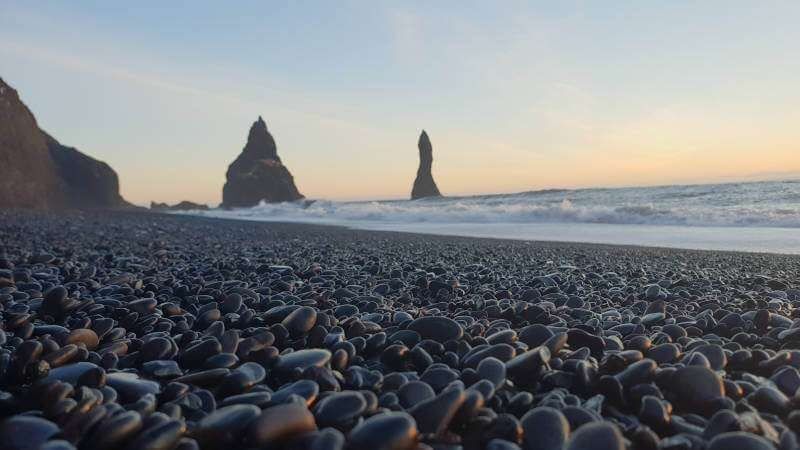 Black Beach Vik seen on a sunset with black pebbles and waves crushing