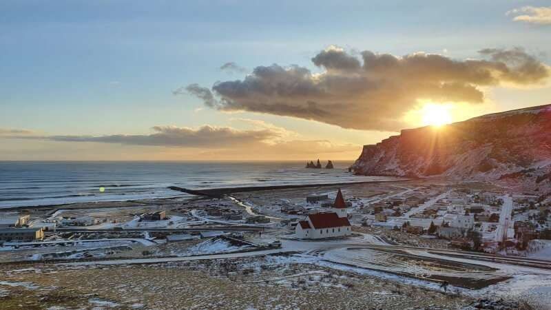 Vik Village, church on the hill and black beach seen on the sunset time
