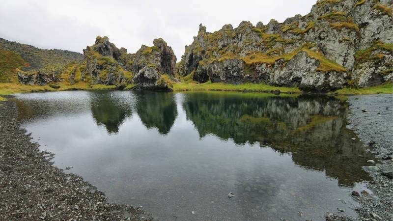 Djupalonssandur with small pond and moss covered rocky hills seen on a cloudy day