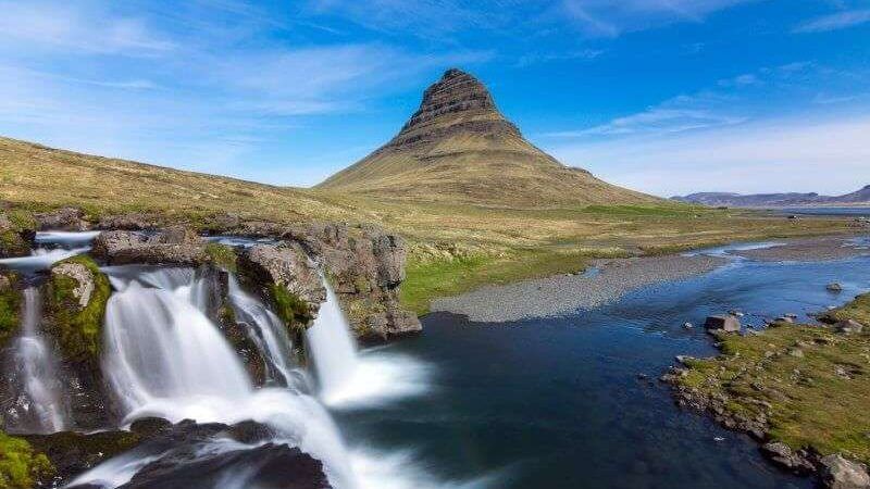 Kirkjufell and small waterfalls nearby on a sunny day