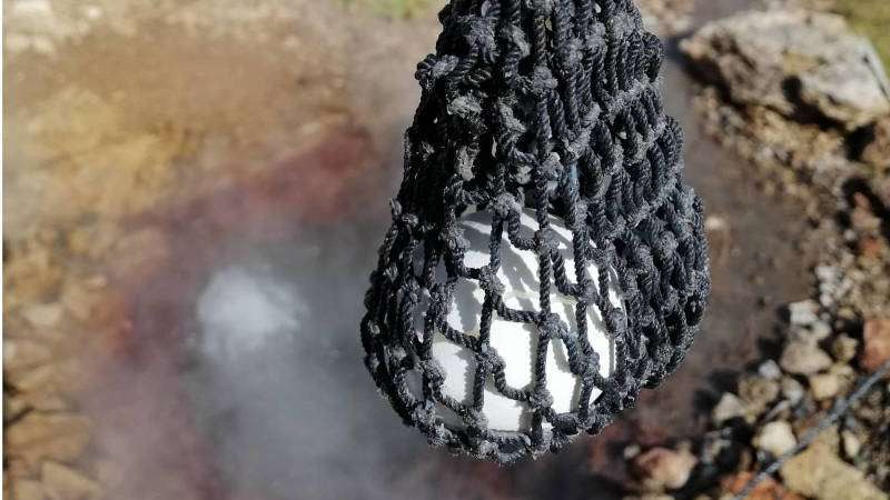 The process of boiling eggs in a geothermal spring using a net