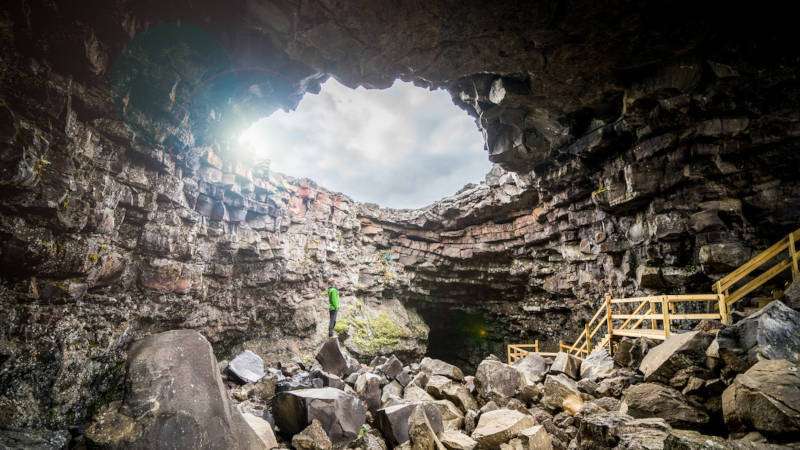 lava cave entrance with a sun shining trough