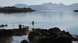 Hvammsvik spa in Iceland with woman swimming in the ocean